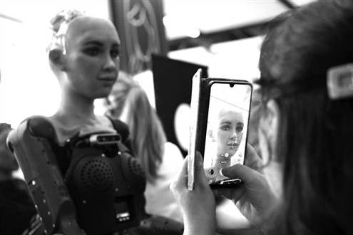 2023年7月7日,在瑞士日内瓦“人工智能造福人类全球峰会”上,一名参会者给仿真机器人索菲亚拍照。新华社发